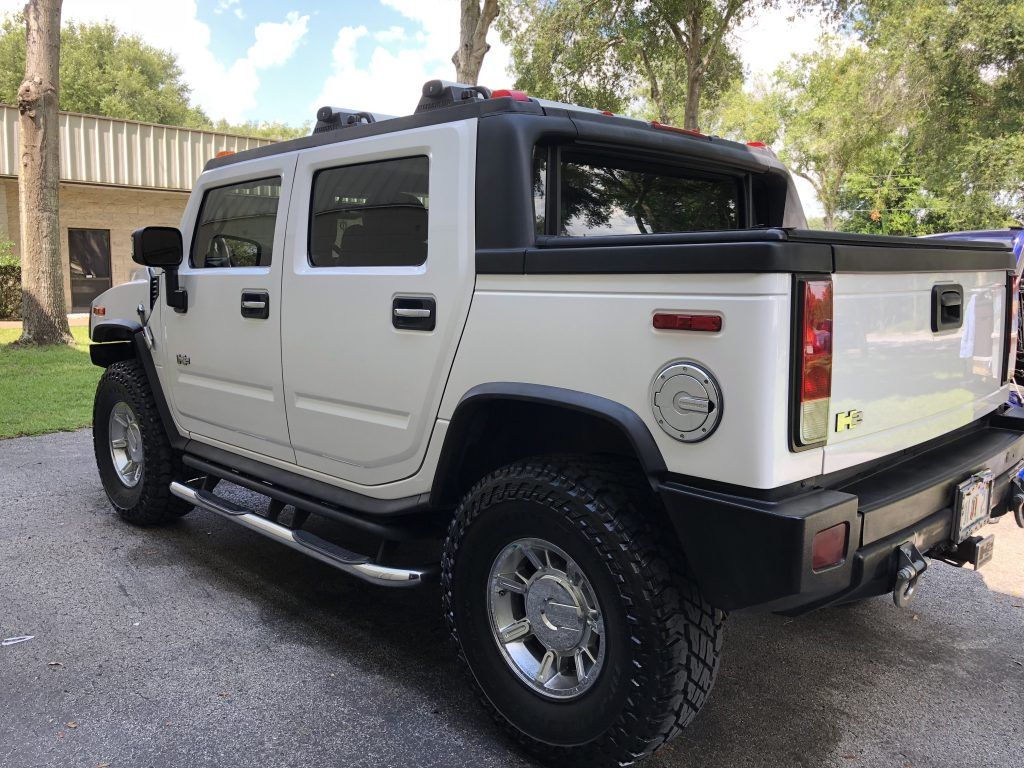 A white hummer h2 is parked in a driveway.