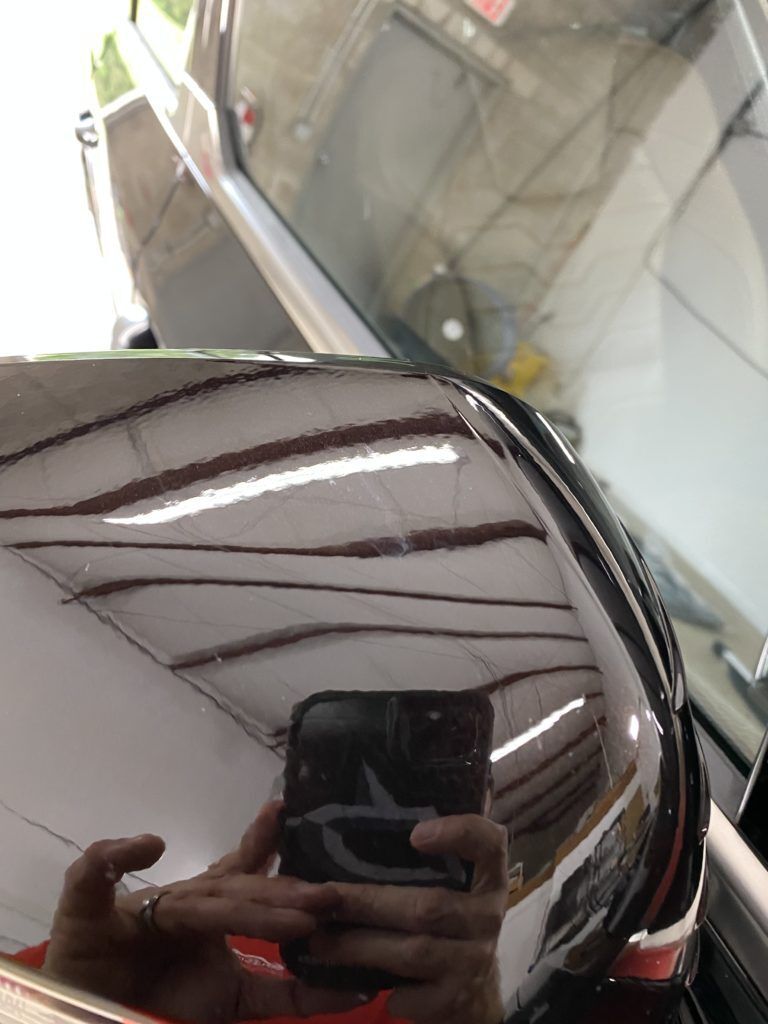 A person is taking a picture of their reflection in a car mirror.
