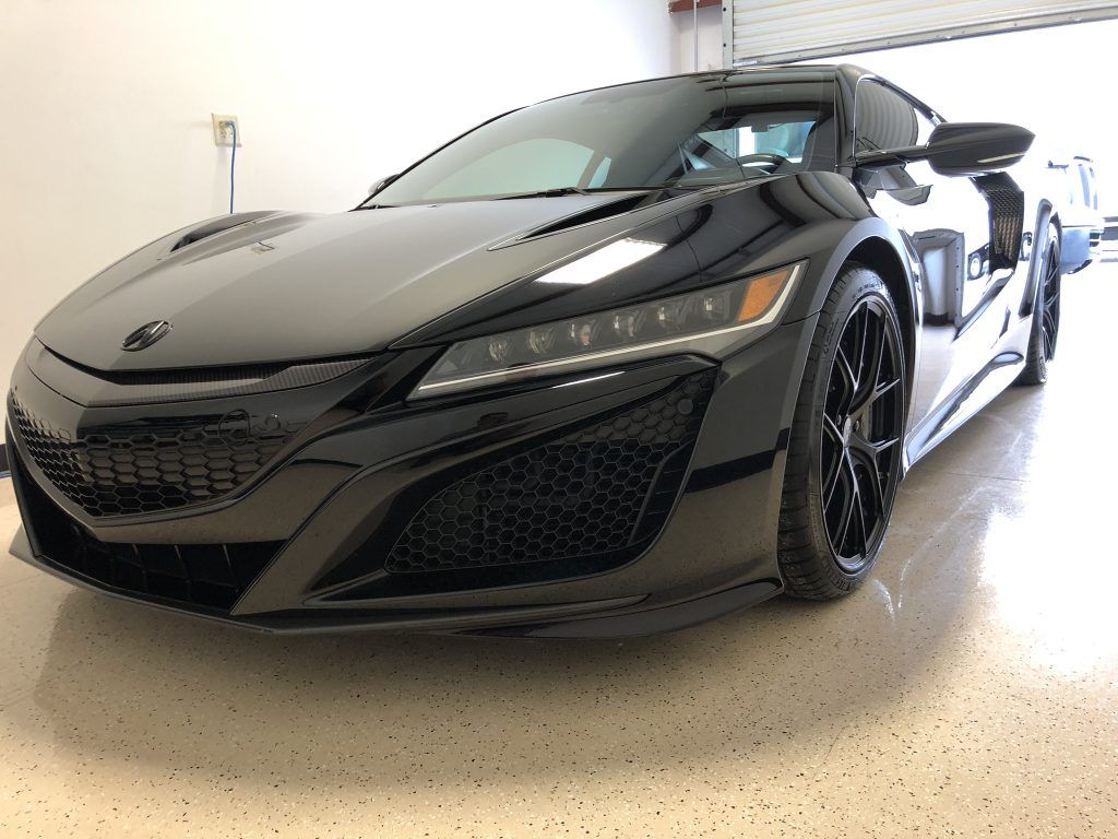 A black sports car is parked in a garage.