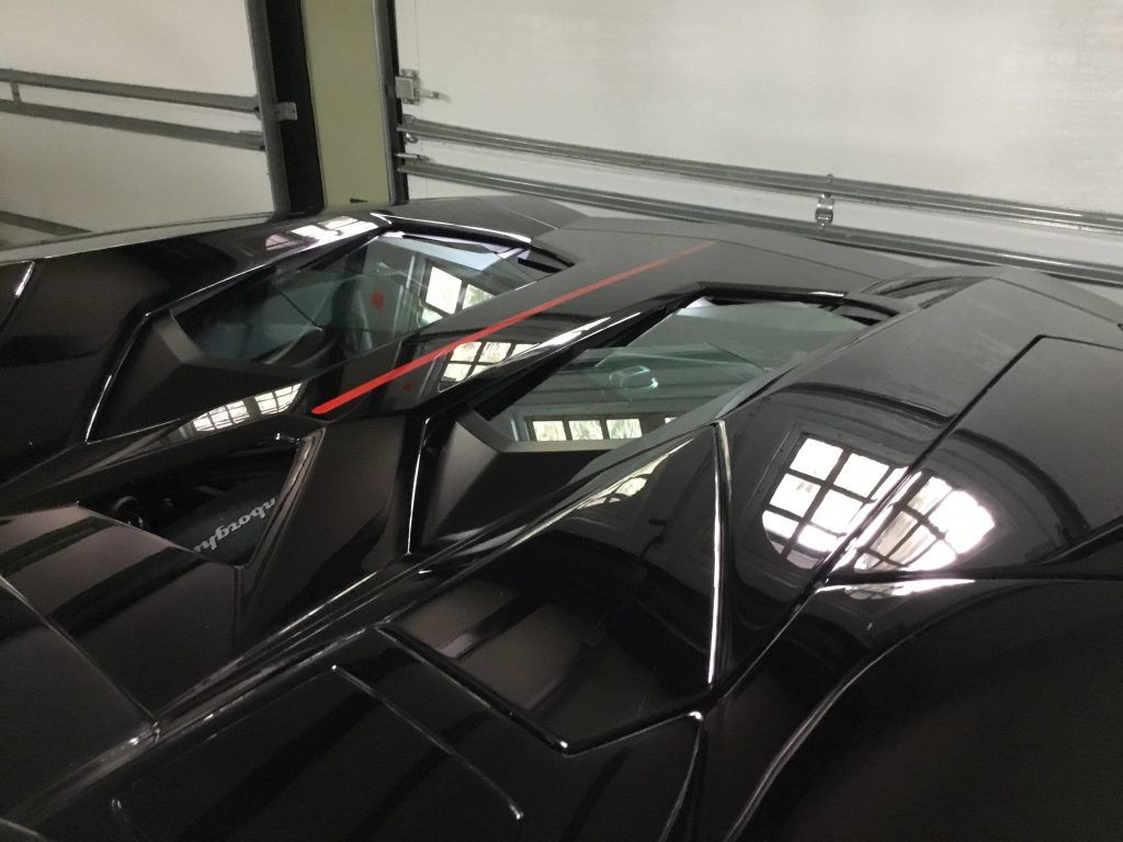 A black sports car with a red stripe on the side is parked in a garage.