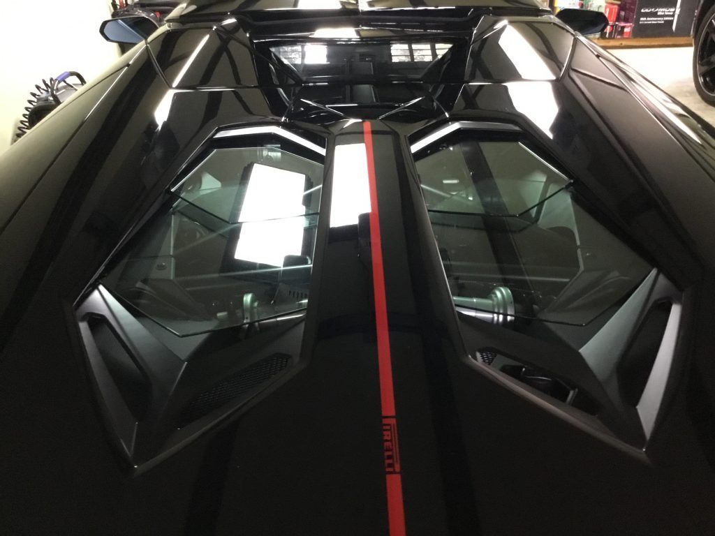 A black car with a red stripe on the side is parked in a garage