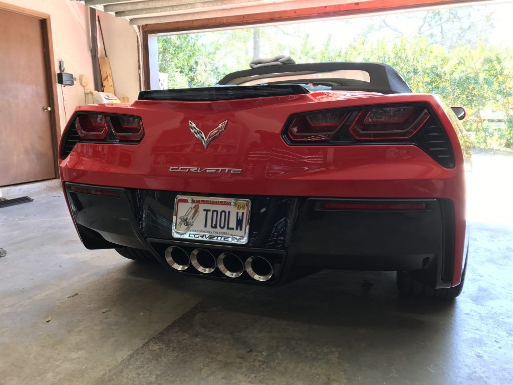A red corvette convertible is parked in a garage.