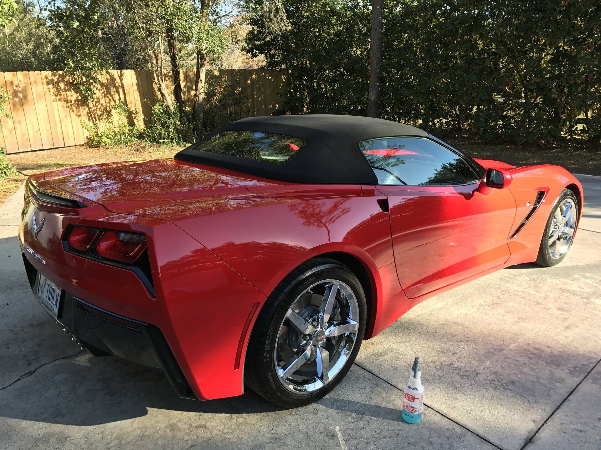 A red sports car with a black top is parked in a driveway.