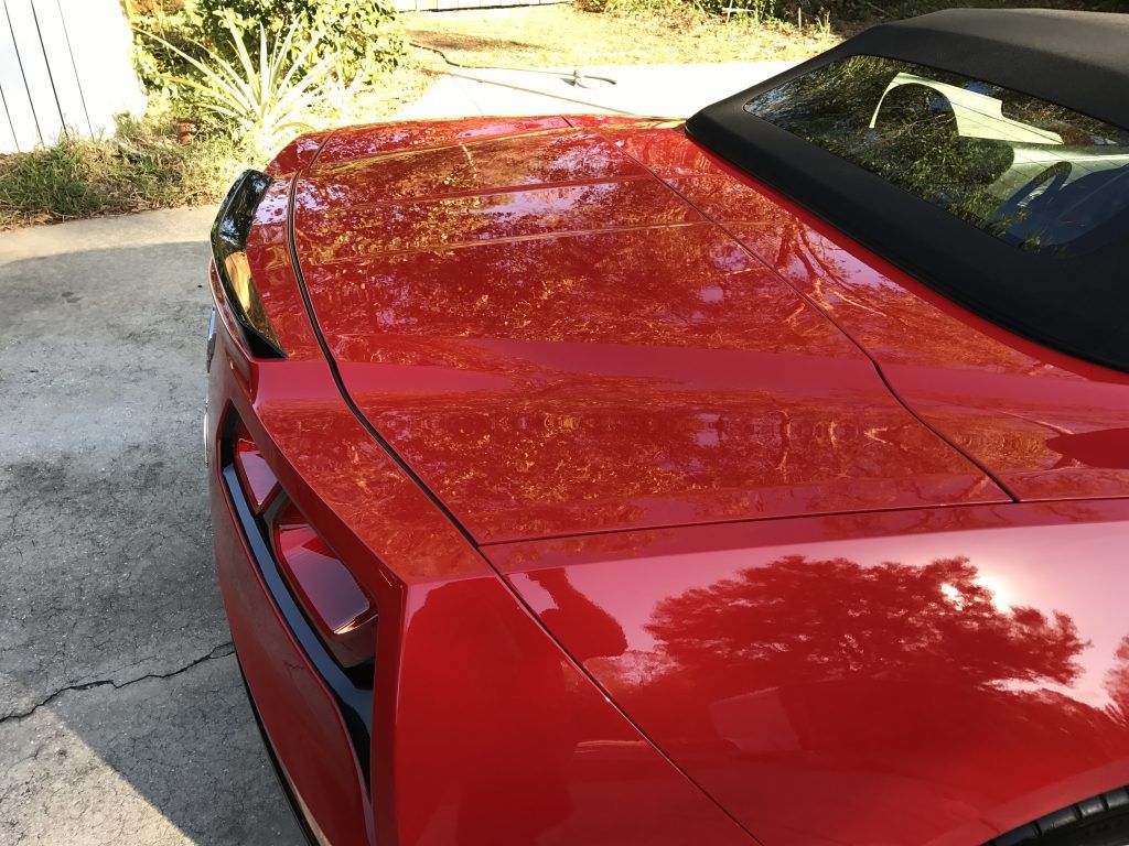 A red sports car with a black top is parked in a driveway.