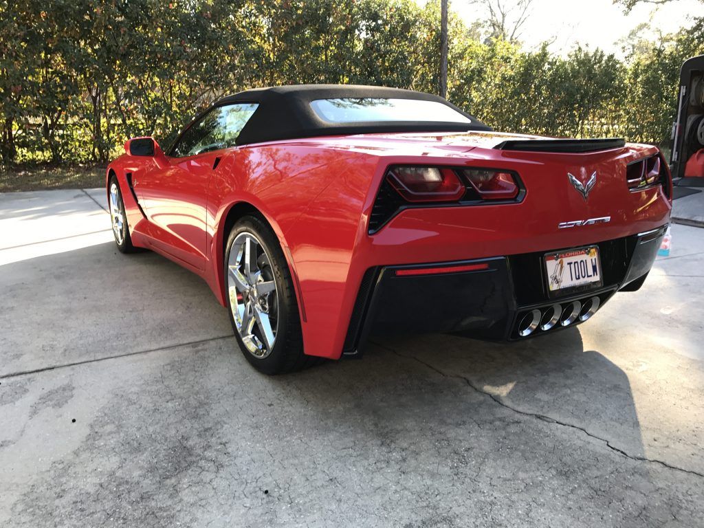 A red corvette convertible is parked in a driveway.