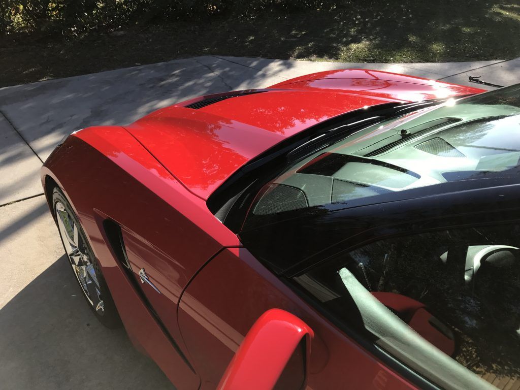 A red sports car is parked in a driveway