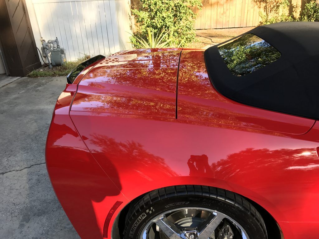 A red car with a black top is parked in a driveway