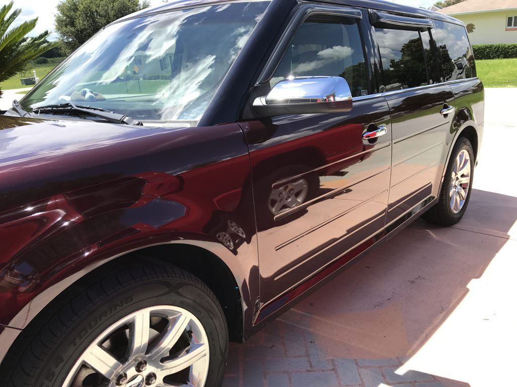 A burgundy suv is parked in a driveway in front of a house