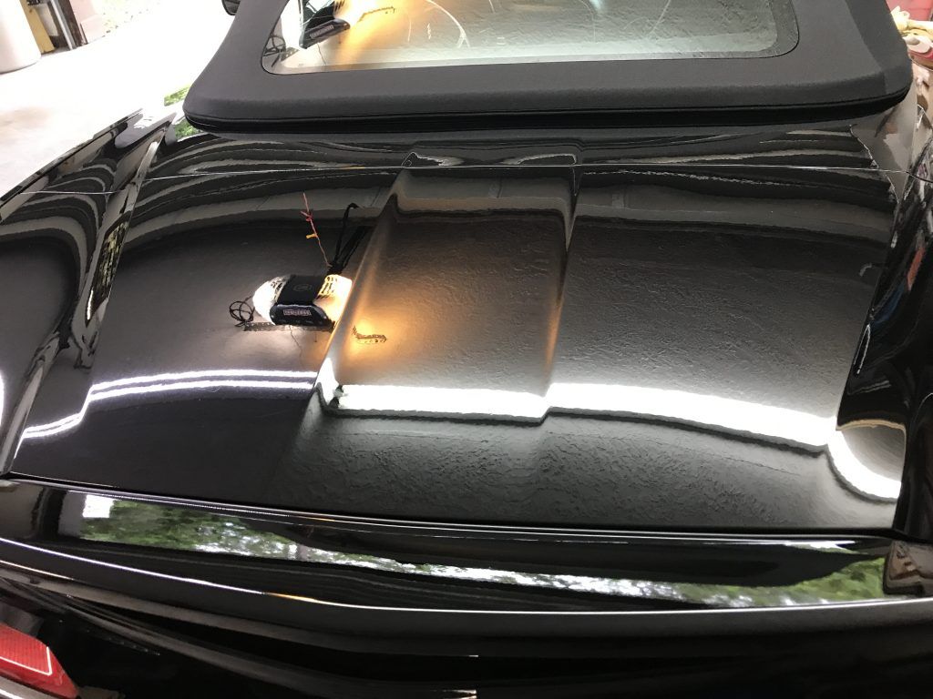 A black car with a convertible top is parked in a garage.