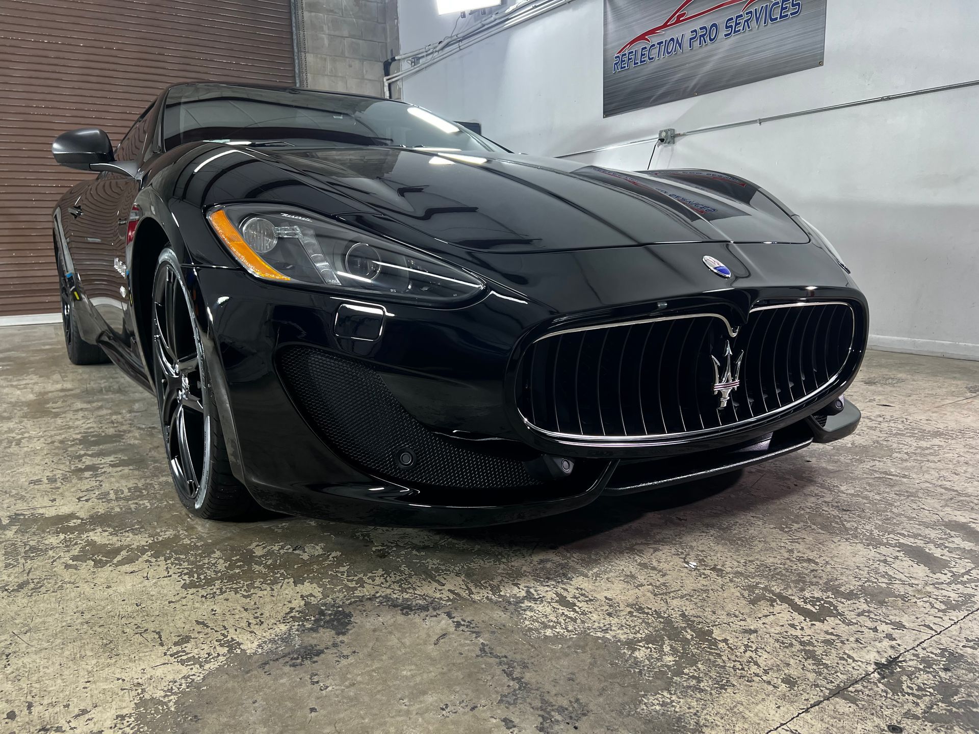 Black Maserati sports car parked in a garage.