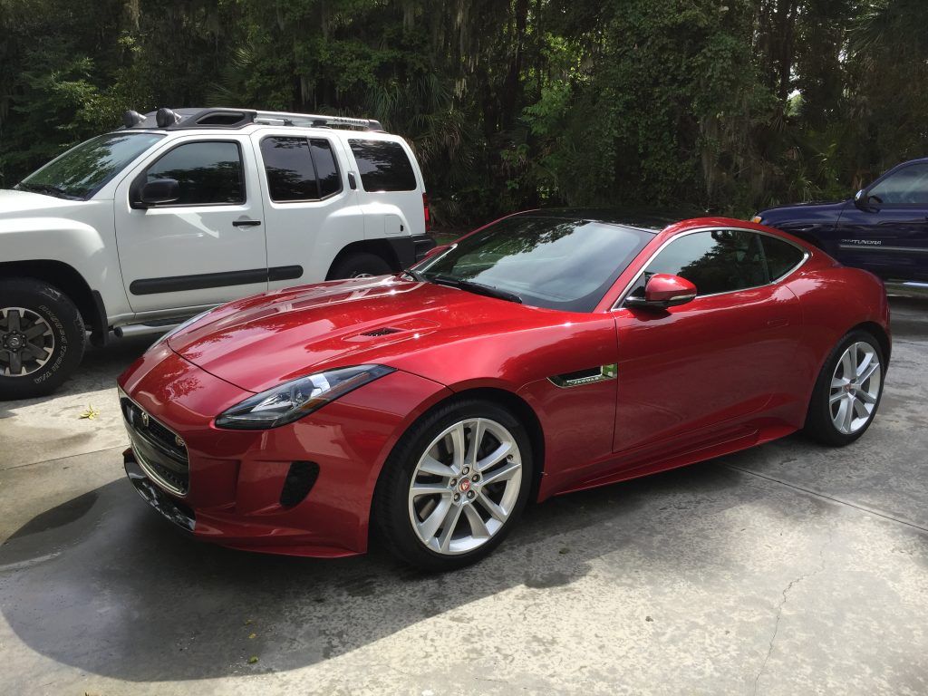 A red sports car is parked next to a white truck.