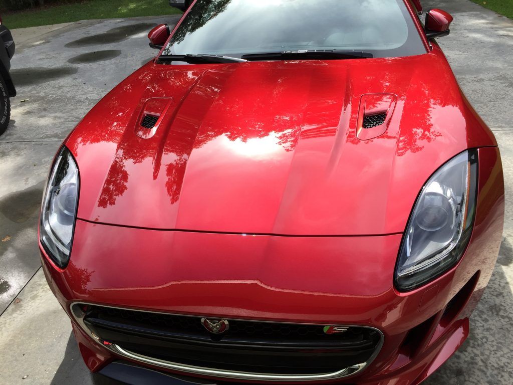 A red jaguar car is parked in a driveway