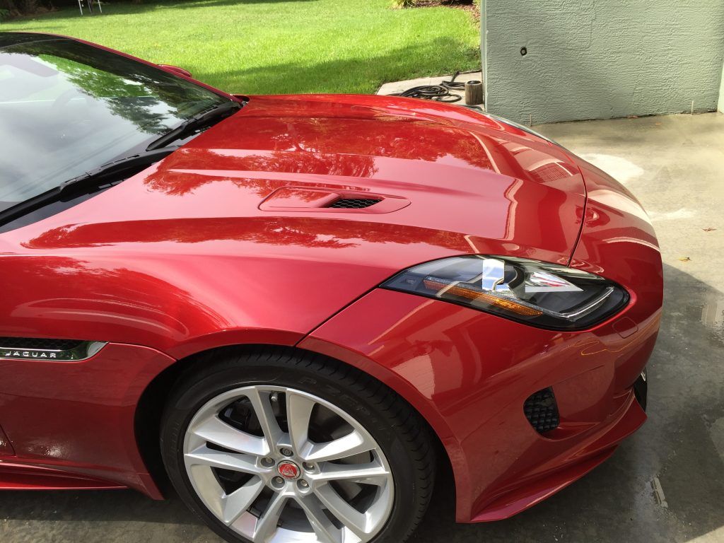 A red sports car is parked in a driveway.