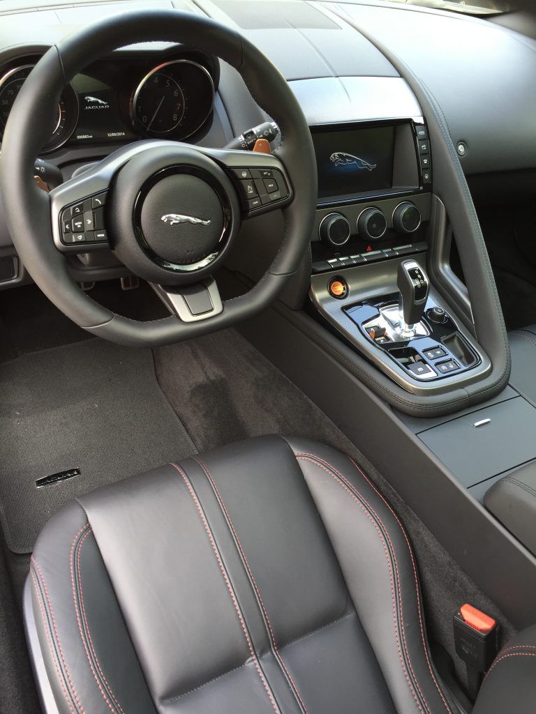 The interior of a car with a jaguar logo on the steering wheel