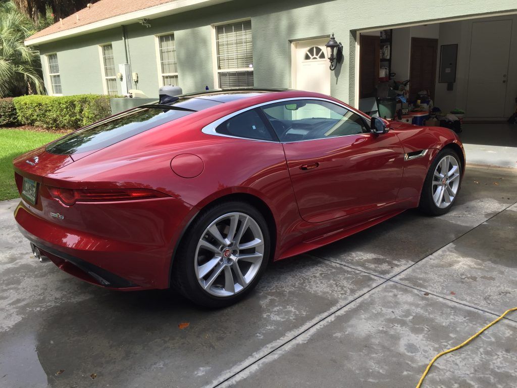 A red sports car is parked in front of a garage.