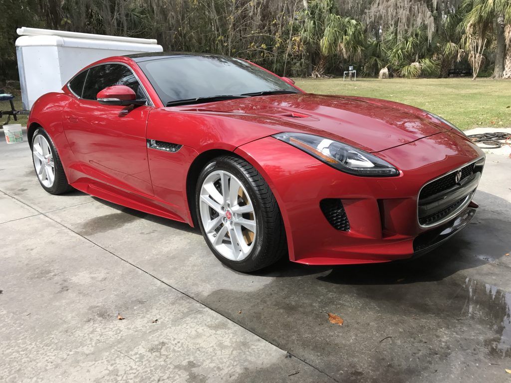 A red jaguar f type is parked in a driveway.