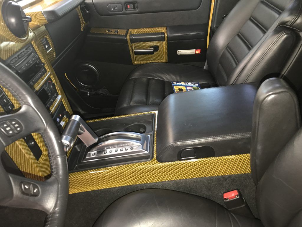 The interior of a hummer h2 with black leather seats and gold trim