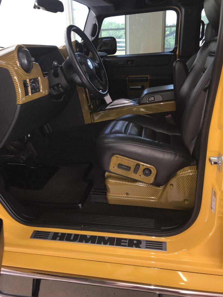 The interior of a yellow hummer truck with the door open.