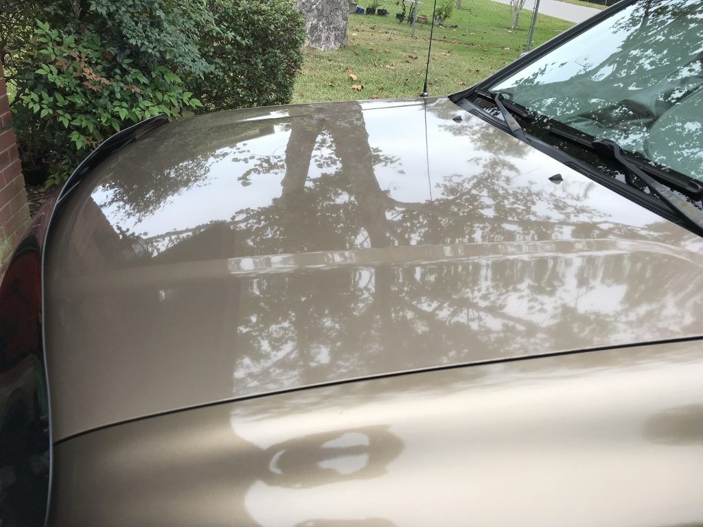 A close up of the hood of a car parked in a driveway.