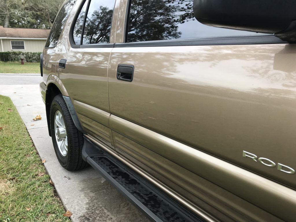 A car is parked on the side of the road in front of a house.
