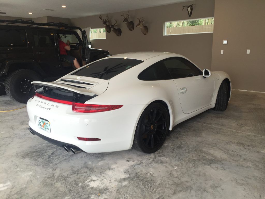 A white porsche 911 is parked in a garage.