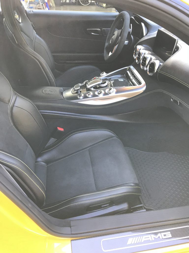 The interior of a yellow sports car with black seats and a steering wheel.