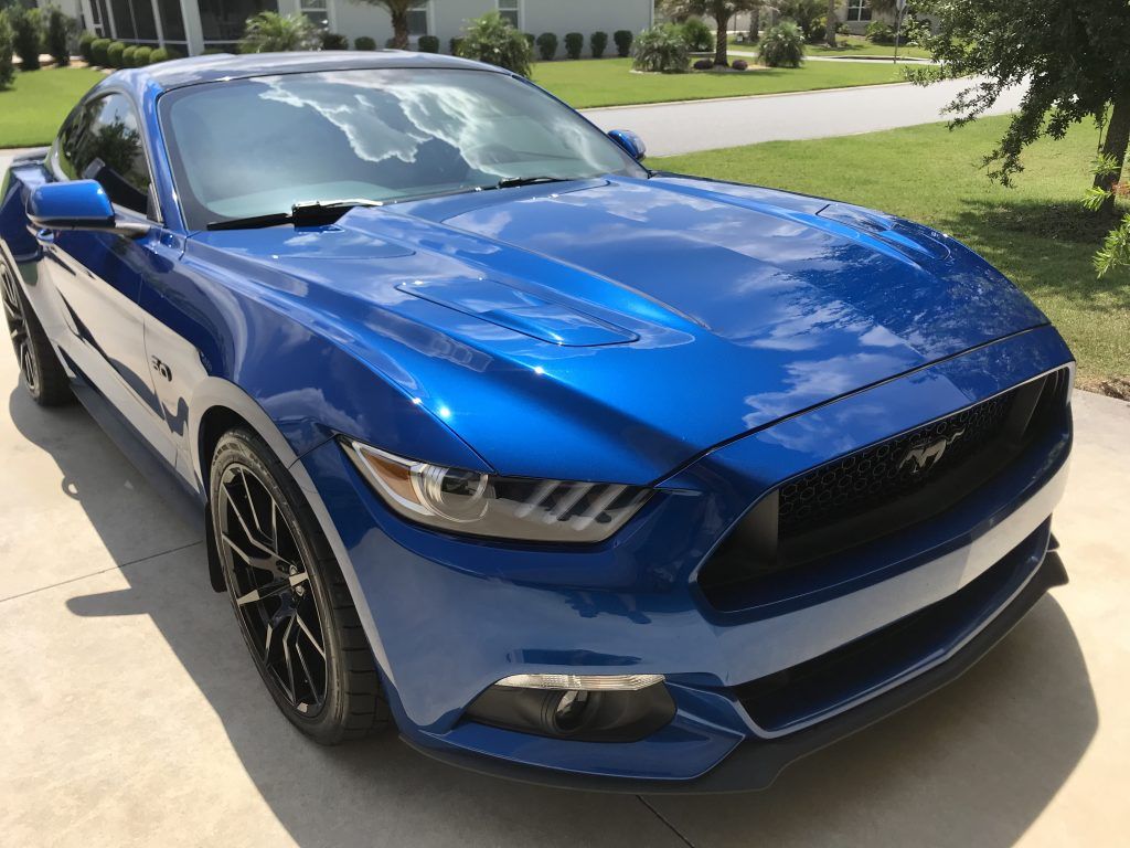 A blue ford mustang is parked in a driveway.