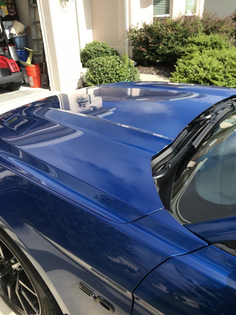 A blue sports car is parked in front of a garage.