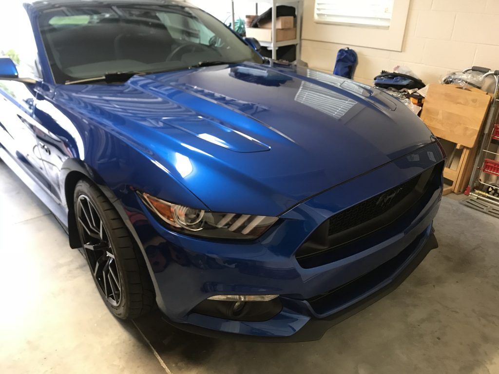 A blue mustang is parked in a garage.