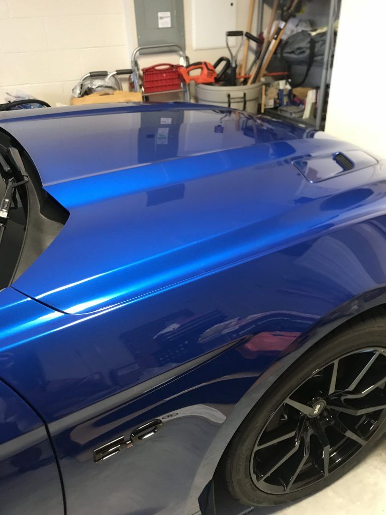A blue car with black wheels is parked in a garage.