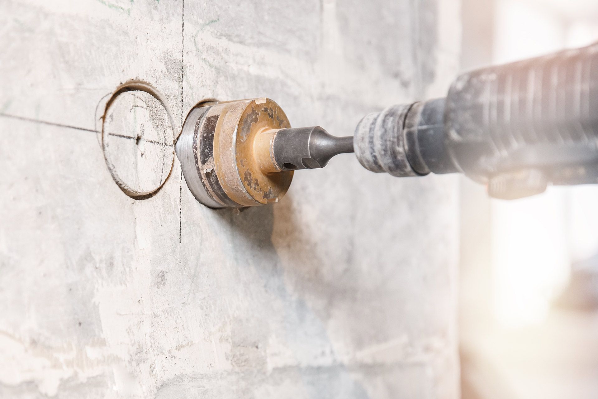 Core drill bit cutting a clean circular hole into a concrete wall.