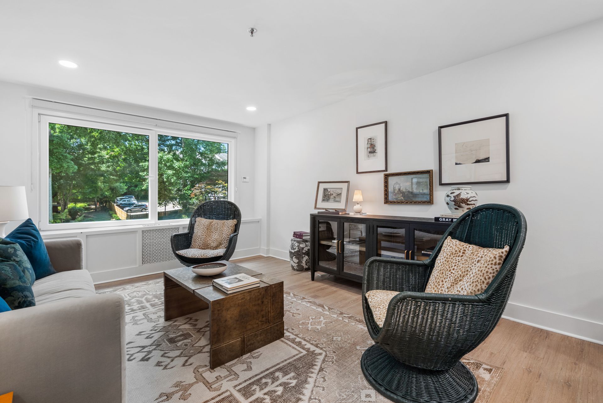 Comfortable rattan lounge chair with a view of the trees outside the living area of a model home at Clairmont Crest senior living apartments in Decatur, GA.