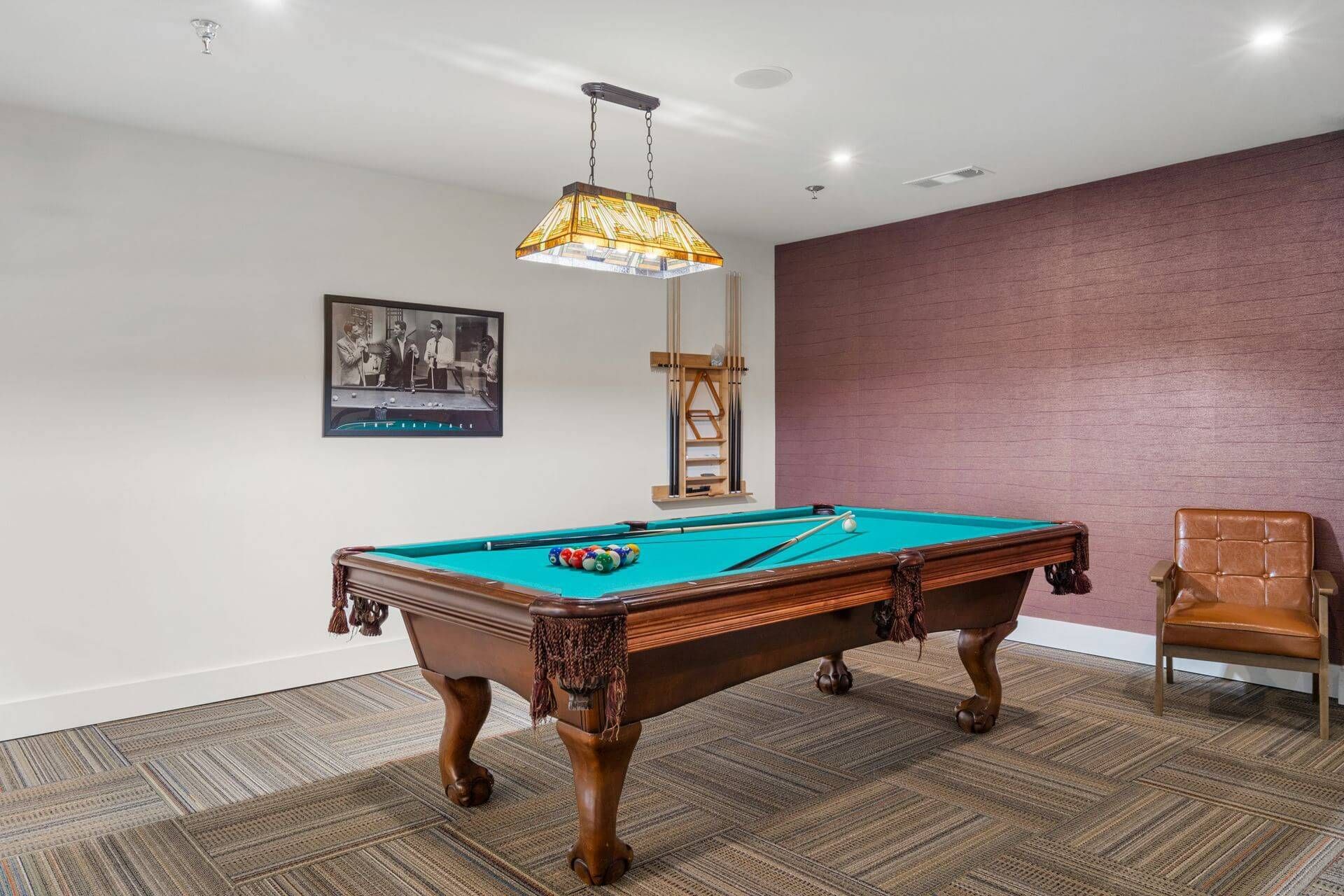Billiards table with a painting on the nearby wall in the game room at Clairmont Crest senior living apartments in Decatur, GA.
