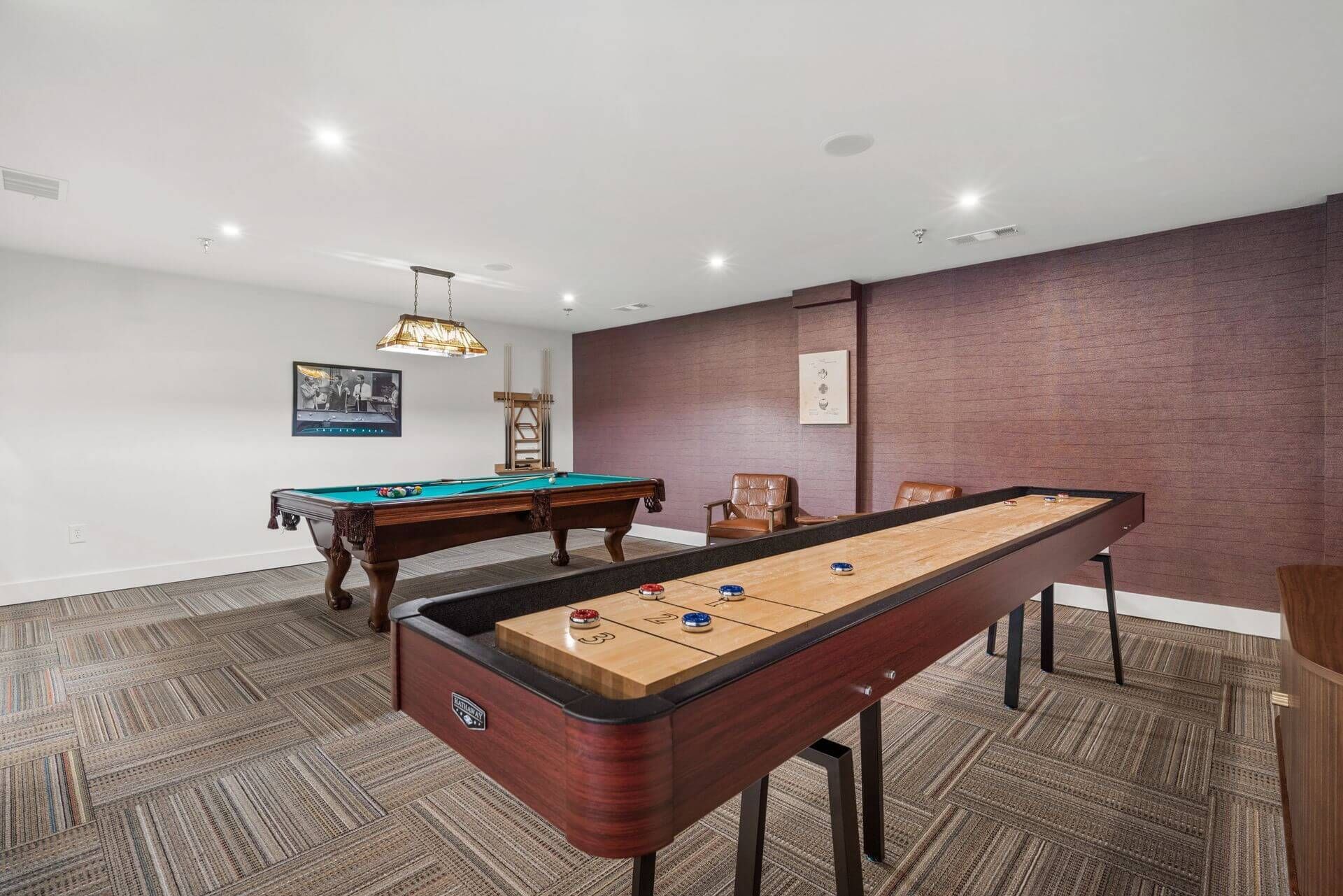View of the billiards table from the tabletop shuffleboard area in the game room at Clairmont Crest senior living apartments in Decatur, GA.