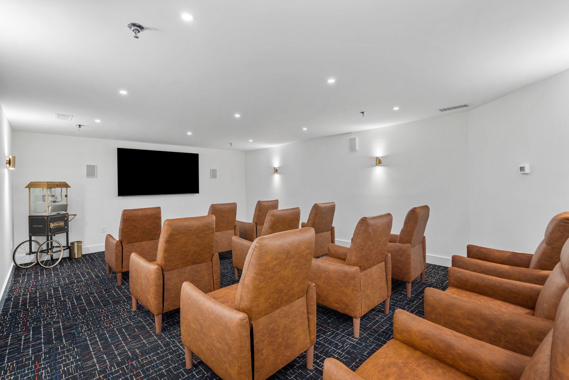 Theater seating and a wall-mounted flatscreen TV in the movie room at Clairmont Crest senior living apartments in Decatur, GA.