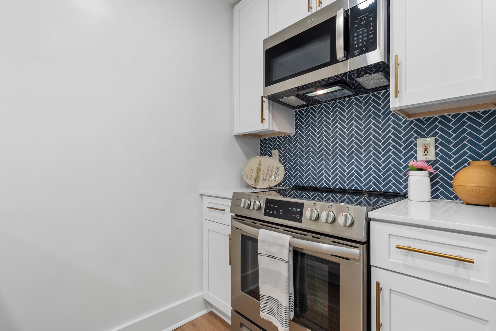 Modern microwave mounted below the cabinetry above the range in a model home's kitchen at Clairmont Crest senior living apartments in Decatur, GA.