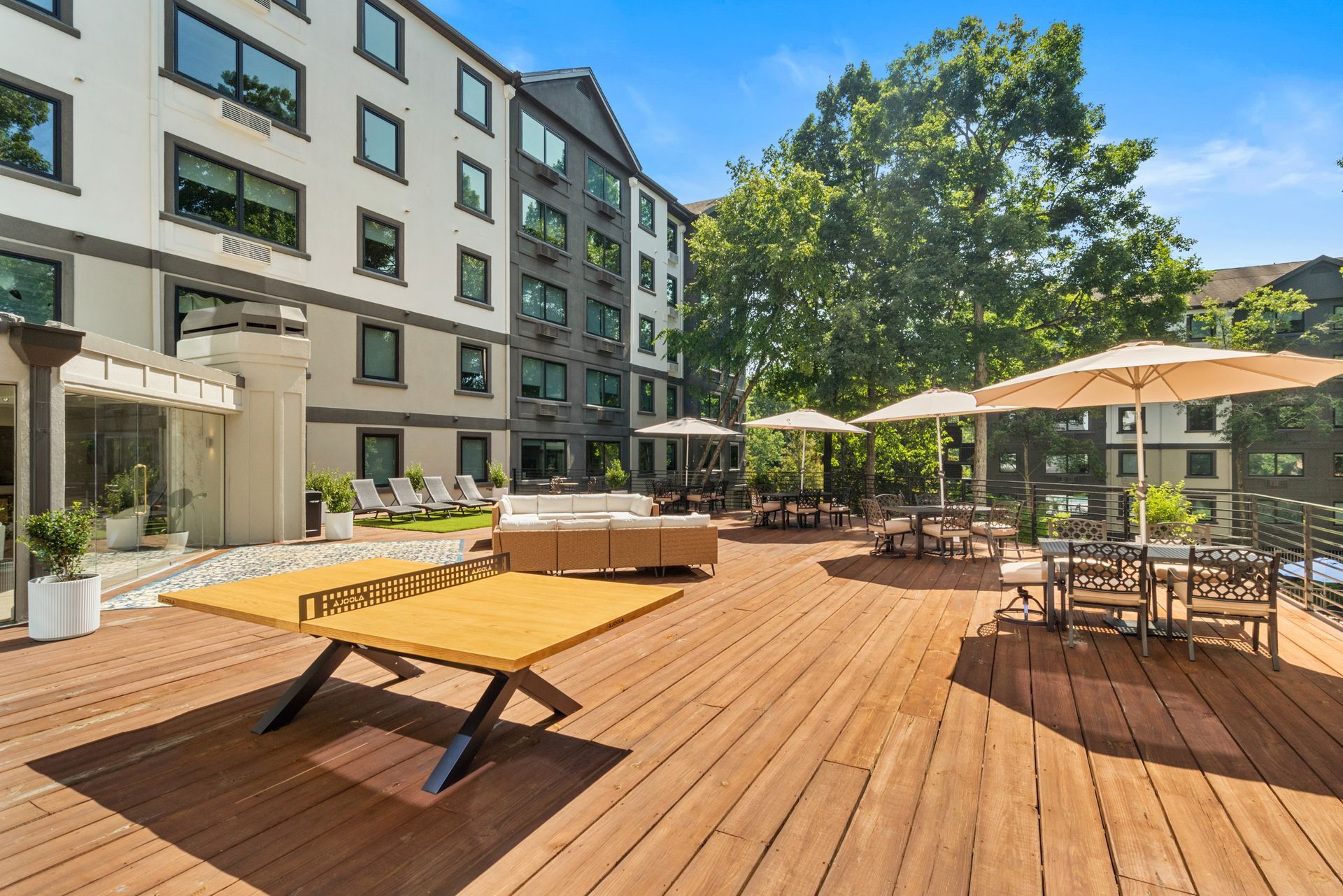 Wooden table tennis area near lounge seating on the outside deck at Clairmont Crest senior living apartments in Decatur, GA.