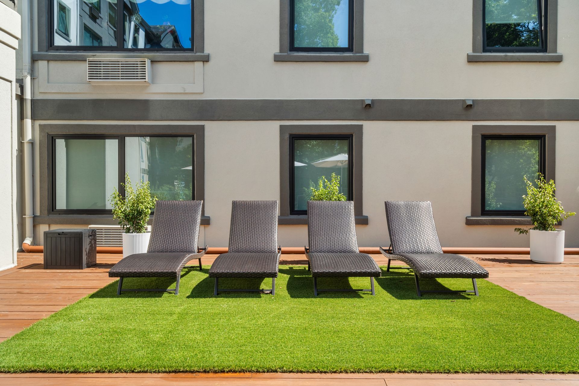 Row of lounge chairs on green turf on the deck outside at Clairmont Crest senior living apartments in Decatur, GA.