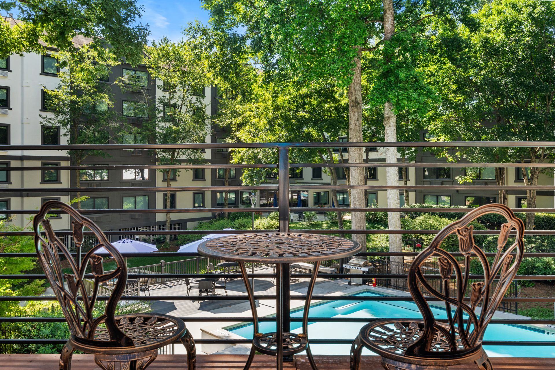 Wrought iron chairs and table overlooking the swimming pool area from a nearby balcony at Clairmont Crest senior living apartments in Decatur, GA.
