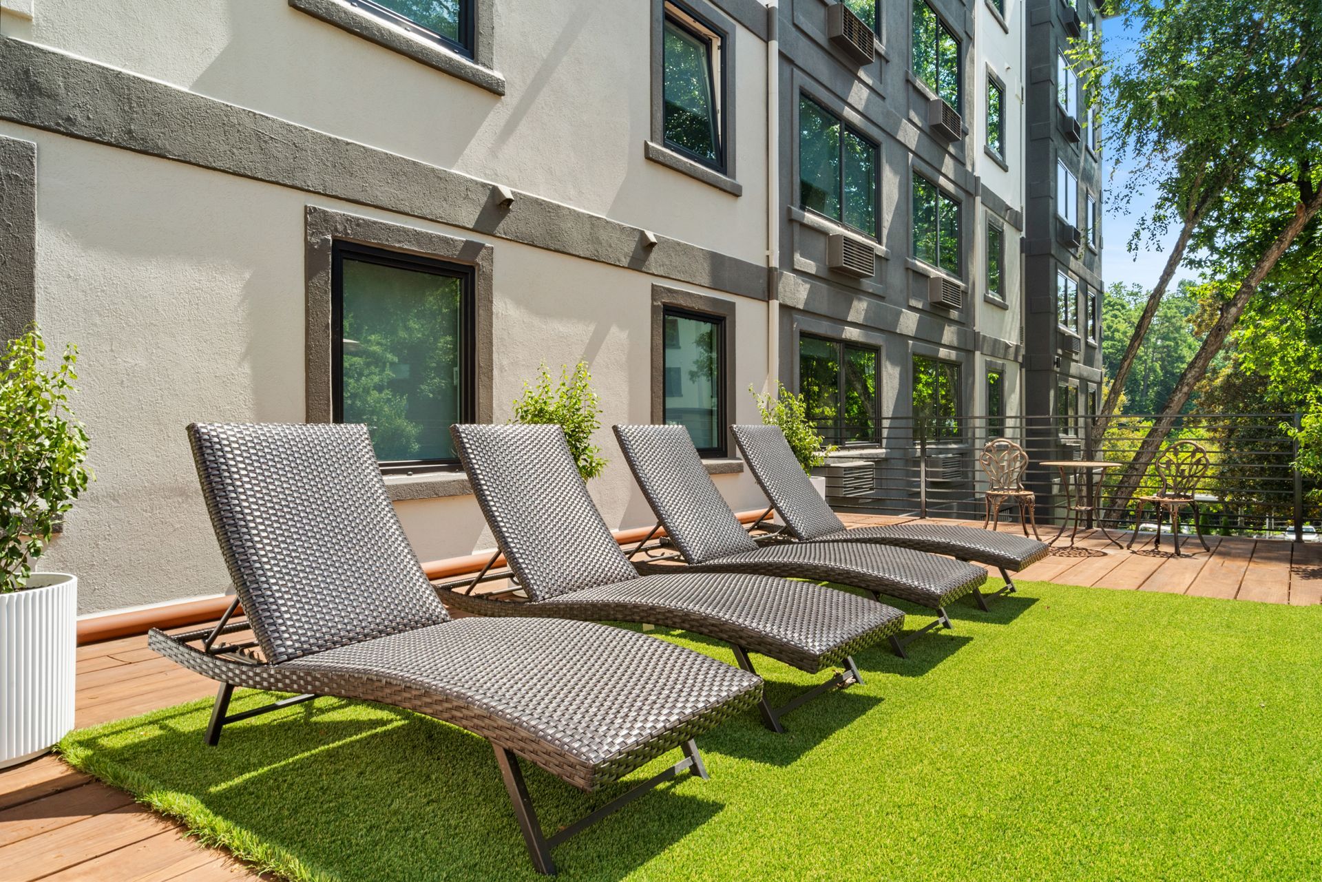 Lounge chairs on green turf on a deck outside at Clairmont Crest senior living apartments in Decatur, GA.
