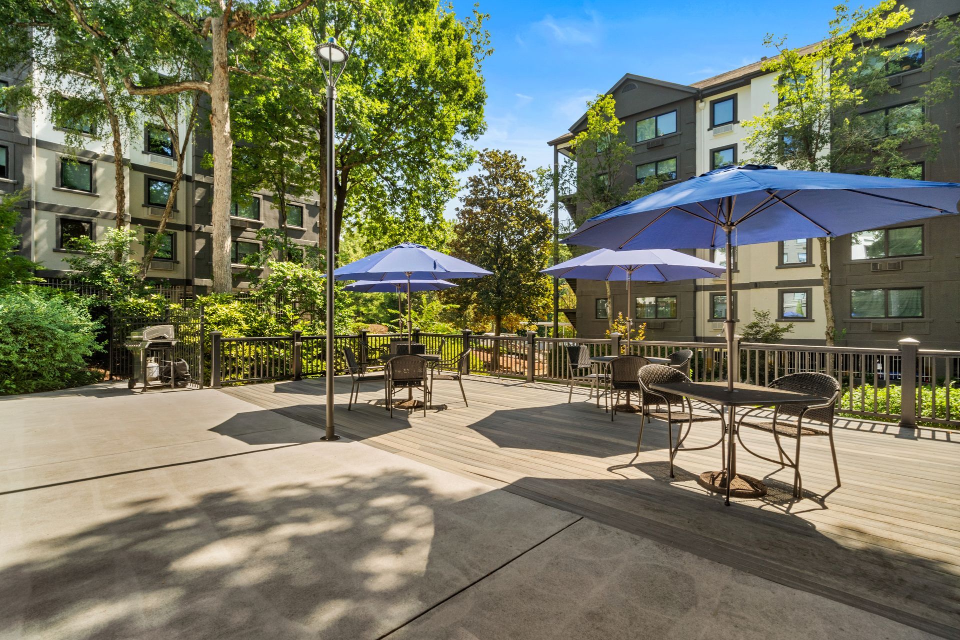 Umbrellas providing shade to seating area near the pool at Clairmont Crest senior living apartments in Decatur, GA.
