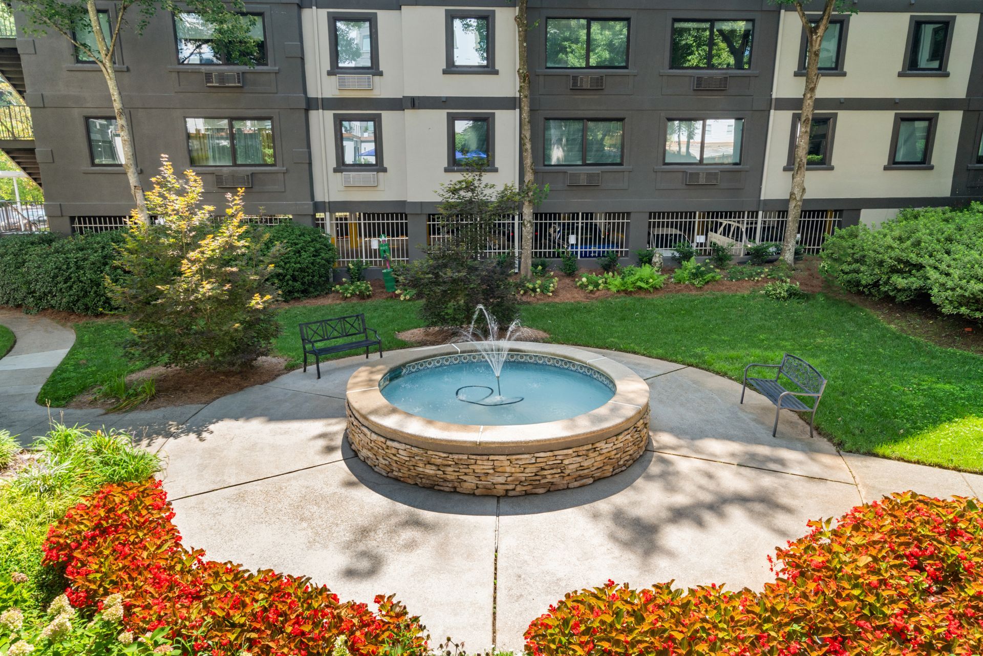 Fountain and flourishing flowers in an exterior courtyard at Clairmont Crest senior living apartments in Decatur, GA.
