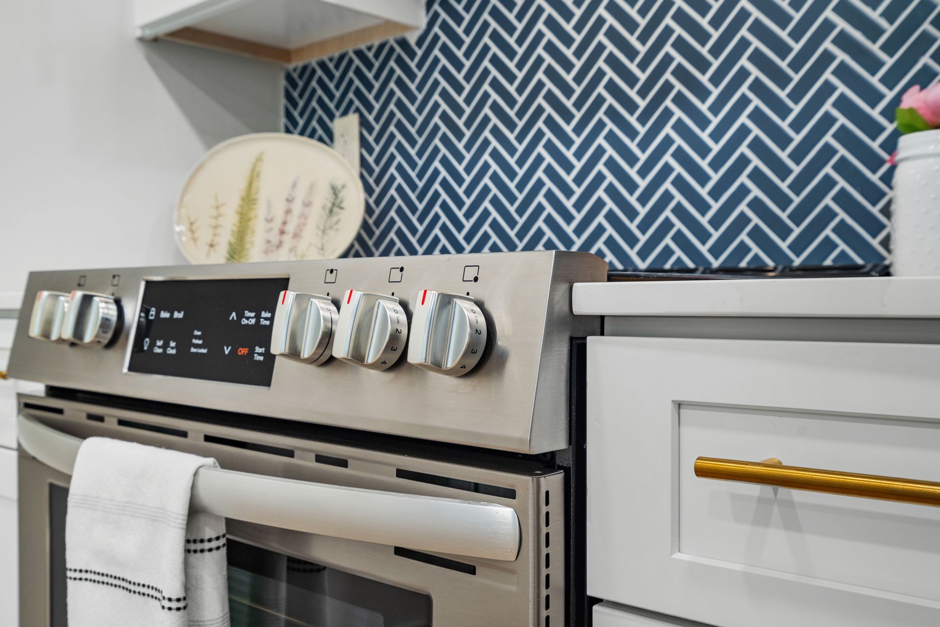 Range with tile backsplash and a nearby drawer with brass handle in a model home's kitchen at Clairmont Crest senior living apartments in Decatur, GA.