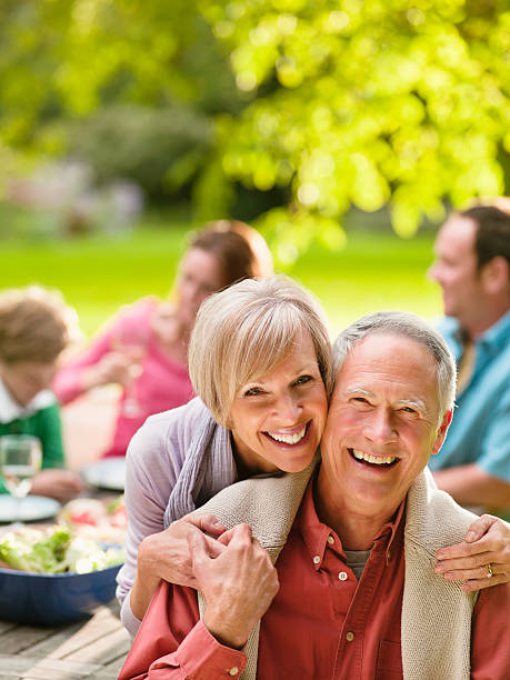 A man and a woman are posing for a picture at a picnic table.