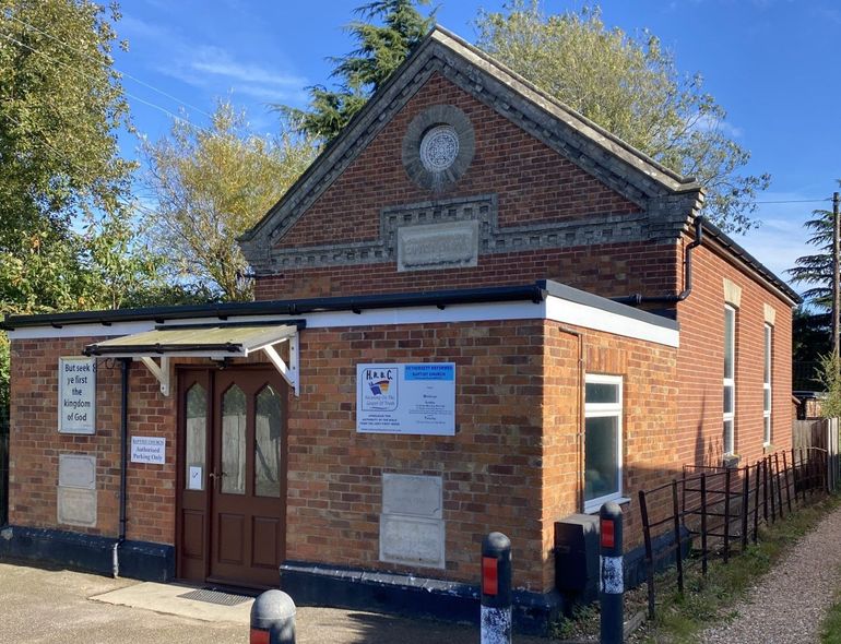 A small brick building with a clock on the side of it.