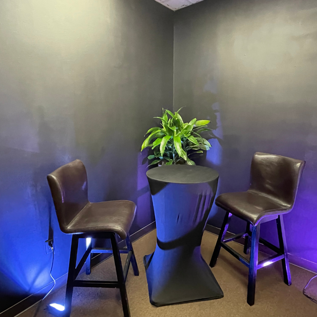 A room with two chairs and a table with a plant on it