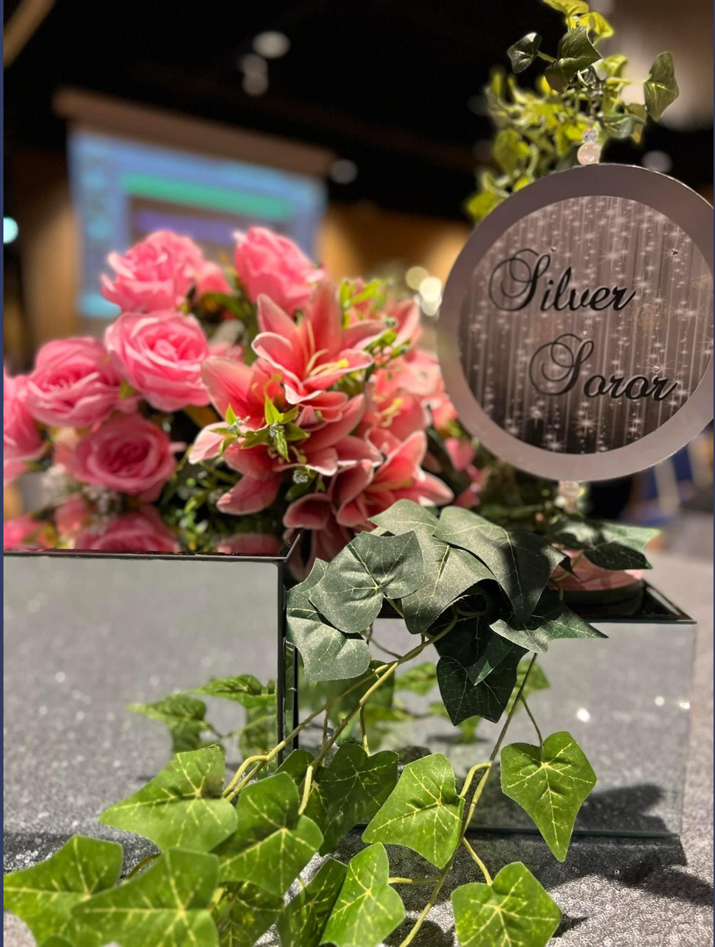A vase filled with pink flowers and green leaves on a table.