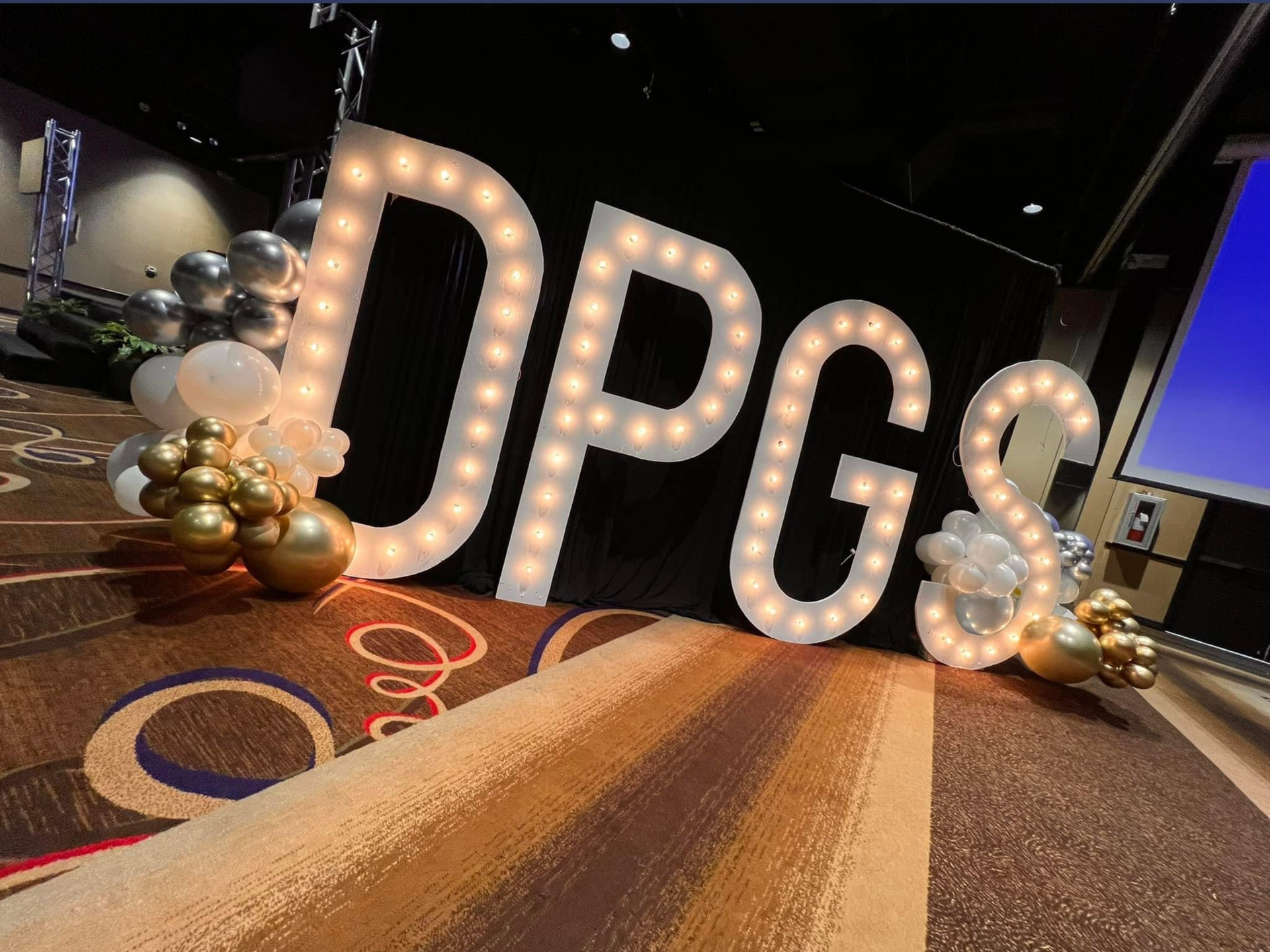 A large lighted sign that says dpgs is sitting on a carpet.