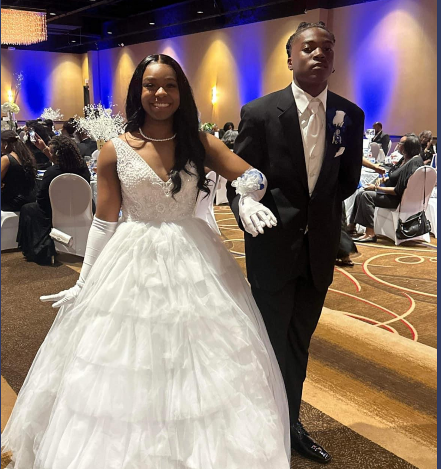 A bride and groom are posing for a picture in a ballroom