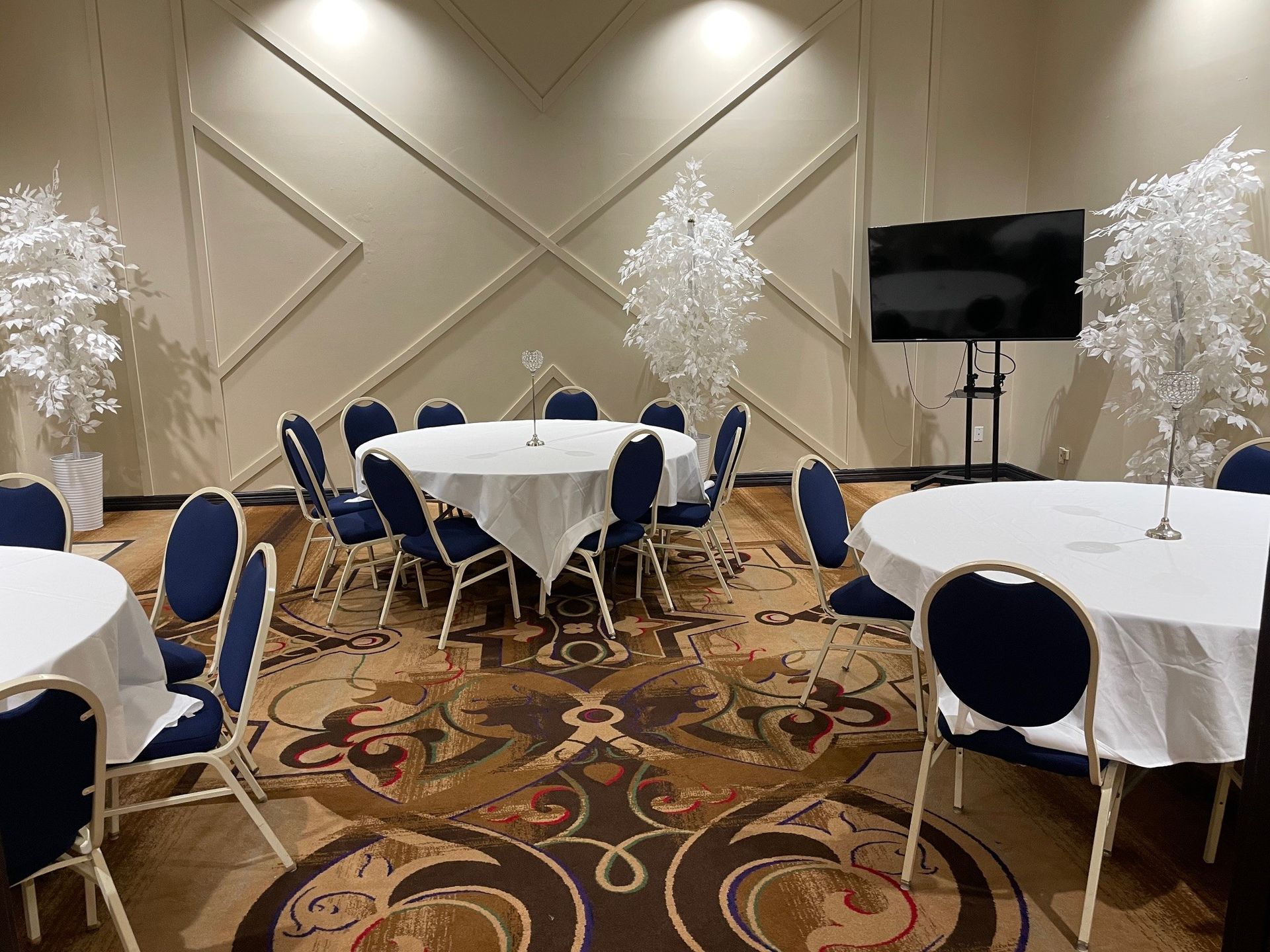 A room with tables and chairs and a flat screen tv.